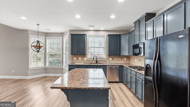 kitchen with baseboards, light wood-type flooring, stainless steel appliances, and a sink