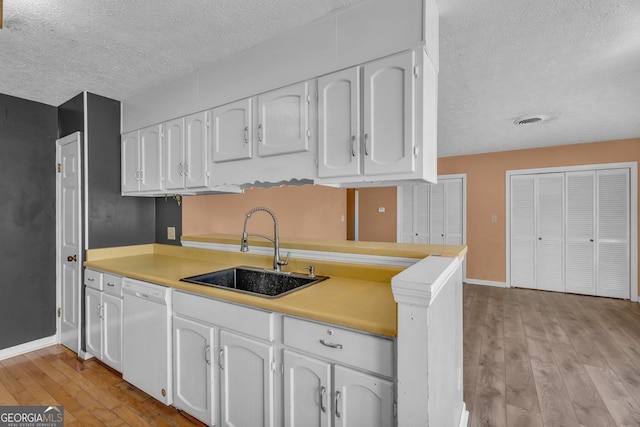 kitchen featuring dishwasher, visible vents, white cabinets, and a sink