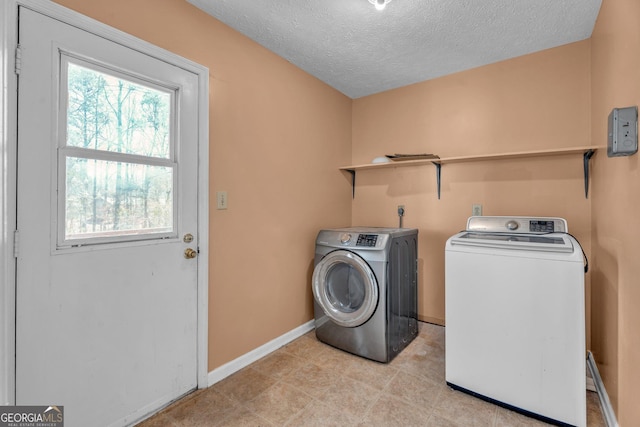 laundry area featuring a textured ceiling, laundry area, independent washer and dryer, and baseboards