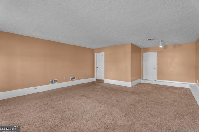 spare room with carpet floors, visible vents, and a textured ceiling