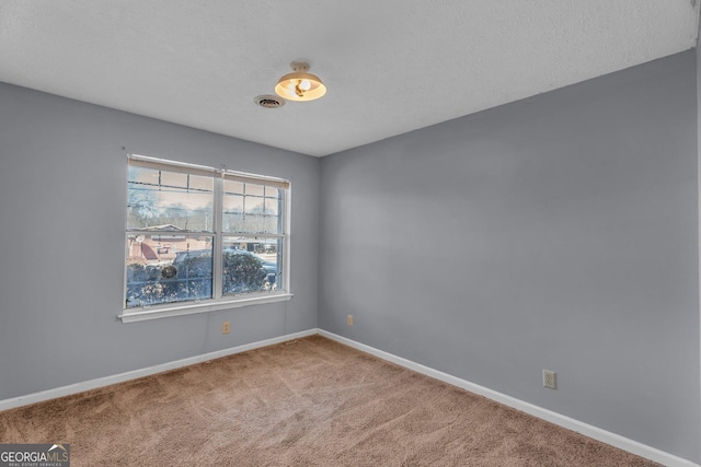 empty room with carpet flooring, visible vents, baseboards, and a textured ceiling