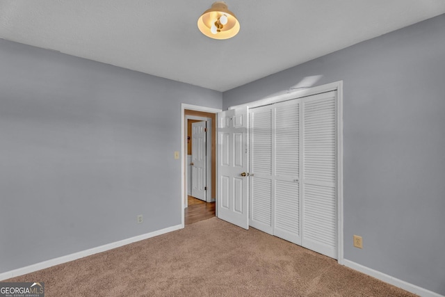 unfurnished bedroom featuring carpet floors, a closet, and baseboards