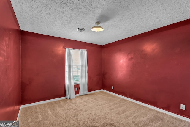 carpeted empty room featuring a textured ceiling, visible vents, and baseboards