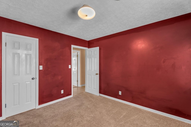 empty room featuring carpet floors, a textured ceiling, and baseboards