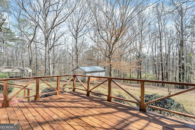 wooden terrace with an outdoor structure and a wooded view