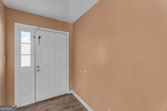 entryway with a textured ceiling, baseboards, and wood finished floors