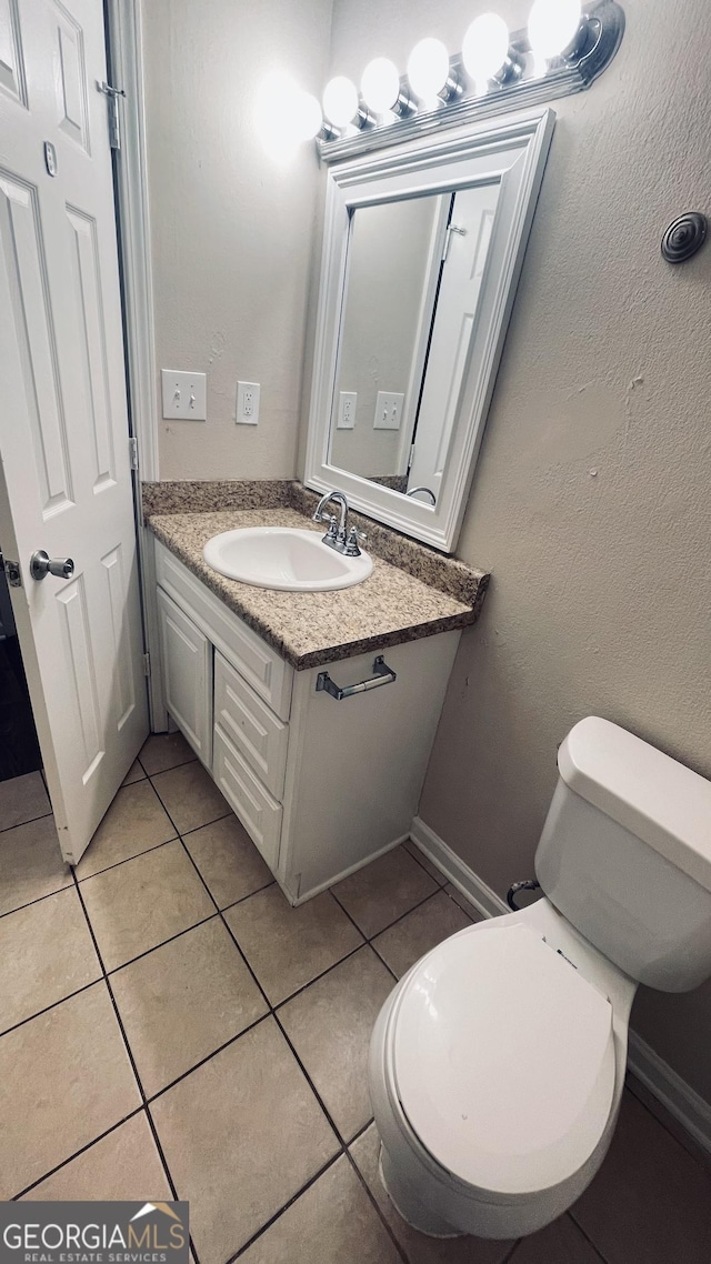 bathroom featuring vanity, tile patterned flooring, toilet, and baseboards