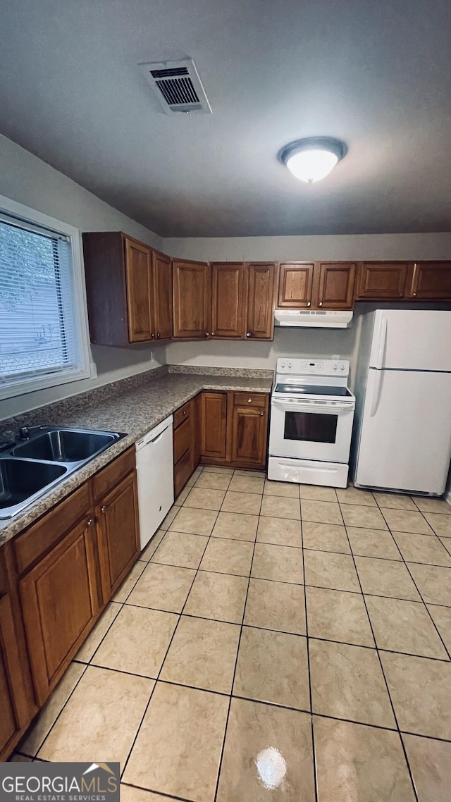 kitchen featuring white appliances, light tile patterned floors, visible vents, under cabinet range hood, and a sink