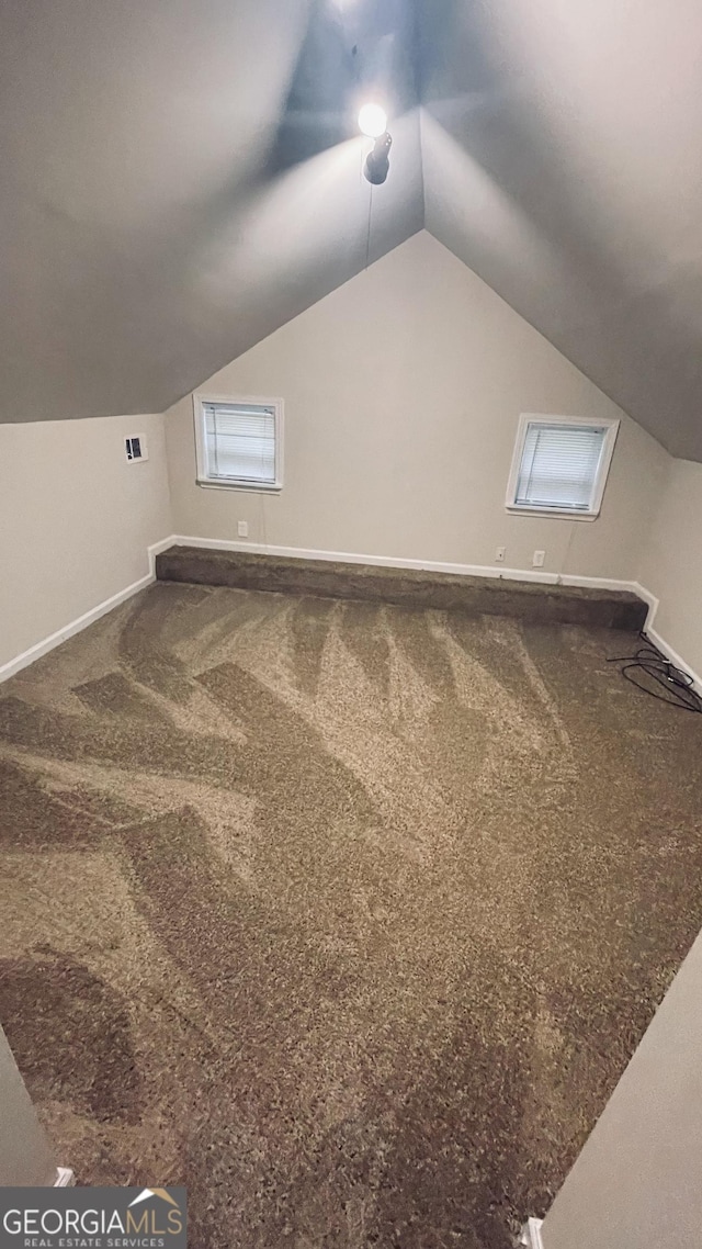 additional living space featuring carpet, visible vents, vaulted ceiling, and baseboards