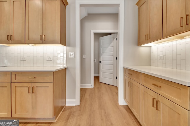 kitchen featuring light brown cabinets, baseboards, light wood-style floors, light countertops, and decorative backsplash