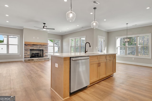 kitchen featuring a sink, light countertops, stainless steel dishwasher, ornamental molding, and light wood finished floors