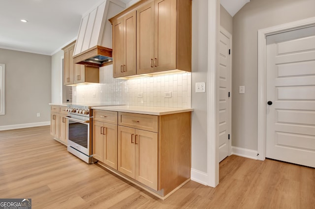 kitchen featuring light wood-style floors, tasteful backsplash, stainless steel range, and light countertops