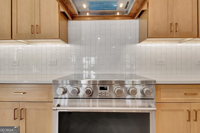 kitchen featuring wall chimney exhaust hood, stainless steel range, decorative backsplash, and light countertops