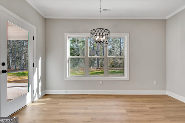 unfurnished dining area featuring light wood-style flooring, a chandelier, baseboards, and ornamental molding