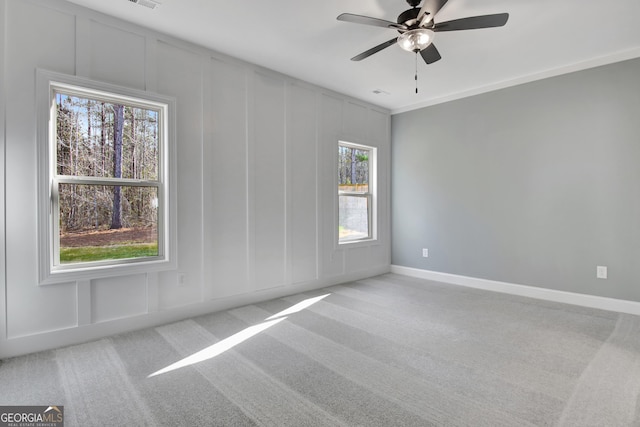 unfurnished room with carpet floors, a decorative wall, baseboards, and ceiling fan