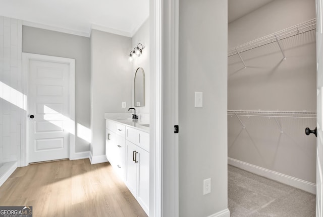 full bath with a spacious closet, baseboards, wood finished floors, and vanity