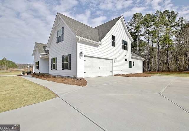 view of property exterior with a garage, concrete driveway, a shingled roof, and a lawn