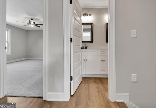 bathroom featuring ceiling fan, wood finished floors, vanity, and baseboards