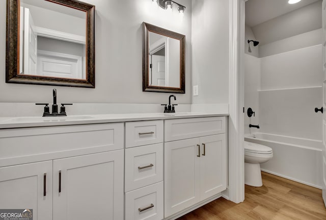 bathroom featuring double vanity, toilet, a sink, shower / tub combination, and wood finished floors