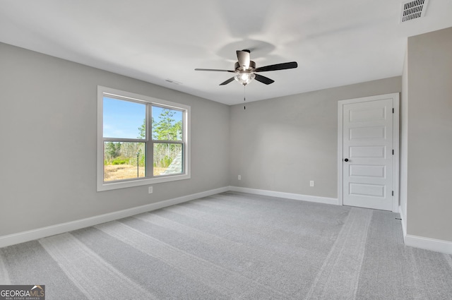 carpeted spare room with ceiling fan, visible vents, and baseboards