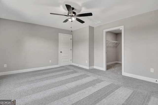 unfurnished bedroom with ceiling fan, carpet floors, visible vents, baseboards, and a spacious closet