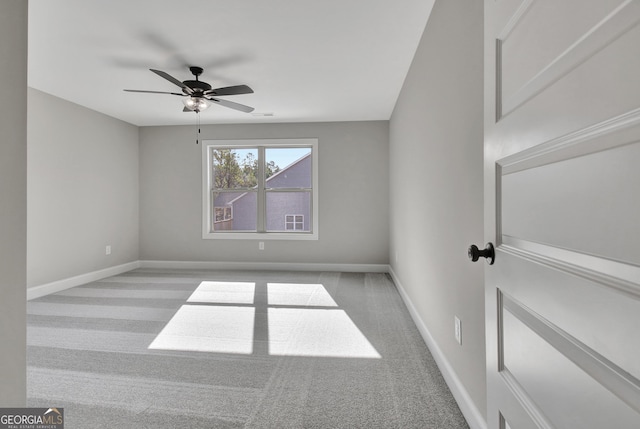 carpeted spare room with ceiling fan and baseboards