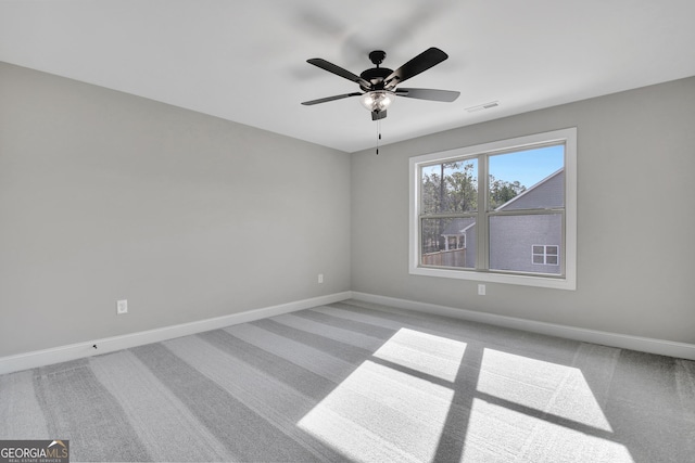 carpeted spare room with baseboards, visible vents, and ceiling fan