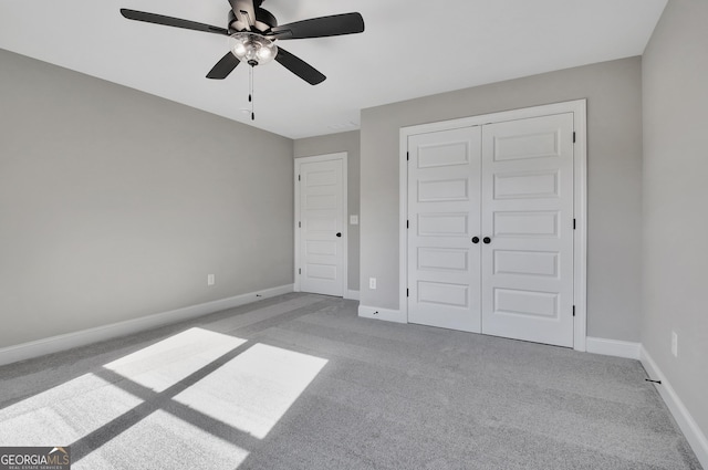 unfurnished bedroom featuring carpet floors, a closet, baseboards, and a ceiling fan