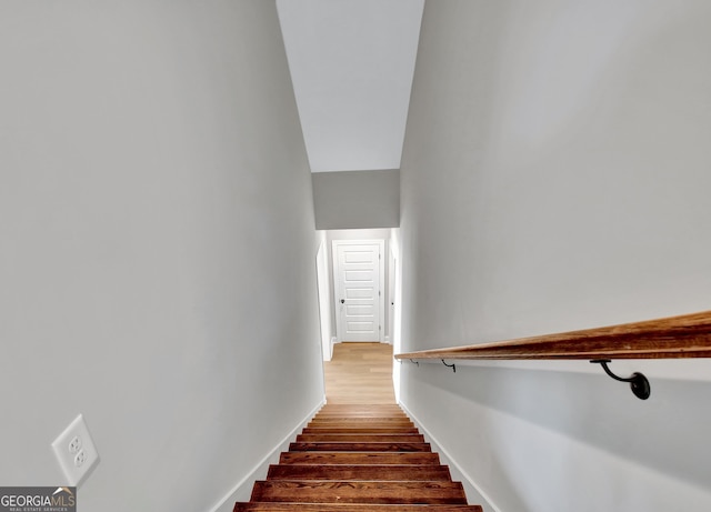 stairway with wood finished floors and baseboards