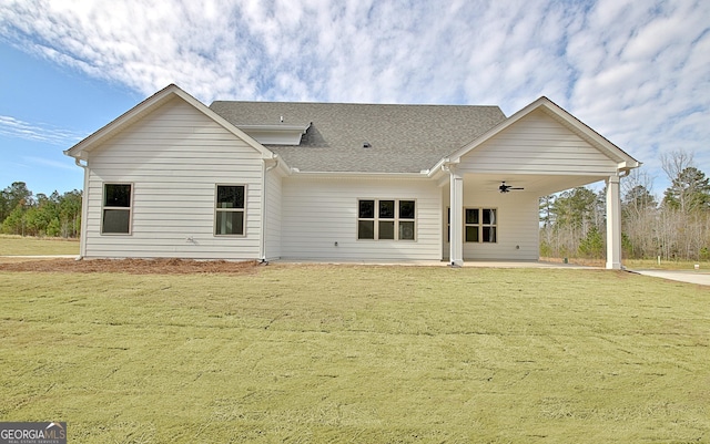 back of property with roof with shingles, a patio, a ceiling fan, and a yard