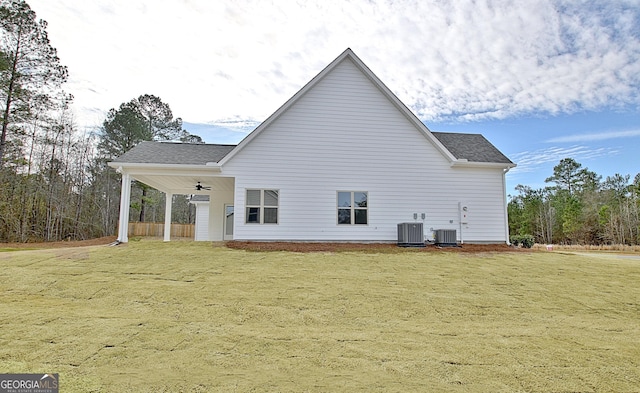 rear view of house with central air condition unit, a ceiling fan, and a yard