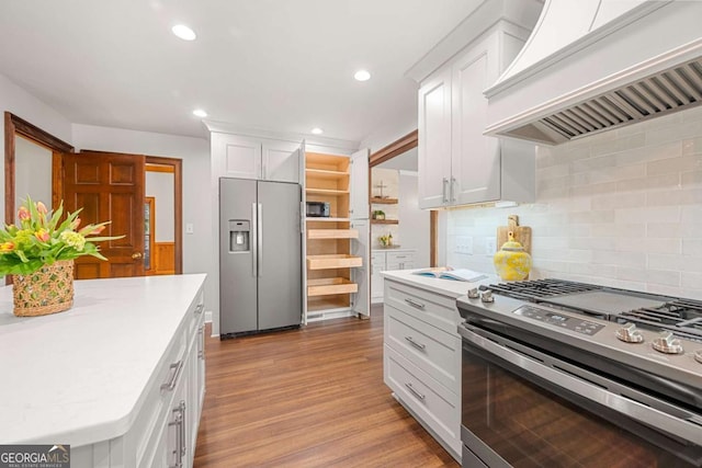 kitchen featuring light wood-style flooring, custom exhaust hood, stainless steel appliances, light countertops, and white cabinetry