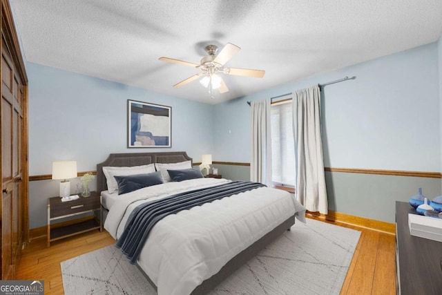 bedroom featuring a textured ceiling, baseboards, and wood finished floors