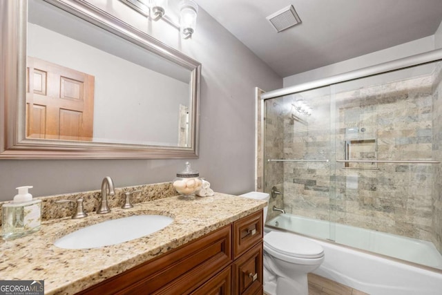 full bath featuring toilet, enclosed tub / shower combo, visible vents, and vanity