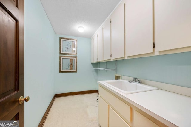 washroom featuring cabinet space, baseboards, a textured ceiling, washer hookup, and a sink