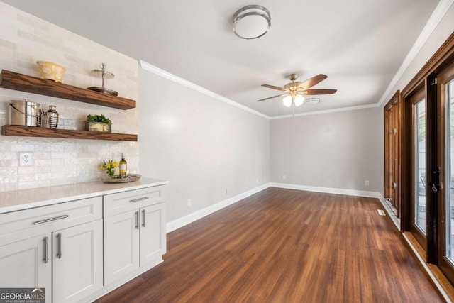 interior space featuring dark wood-style floors, ceiling fan, baseboards, and crown molding