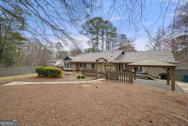 ranch-style home with a shingled roof, fence private yard, and a gazebo