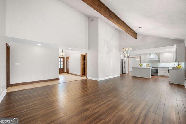 unfurnished living room featuring high vaulted ceiling, dark wood-type flooring, baseboards, beam ceiling, and an inviting chandelier