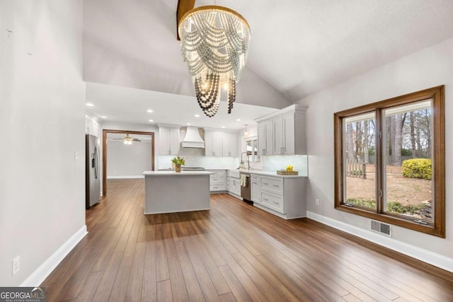 kitchen with visible vents, dark wood-style flooring, stainless steel appliances, premium range hood, and a notable chandelier