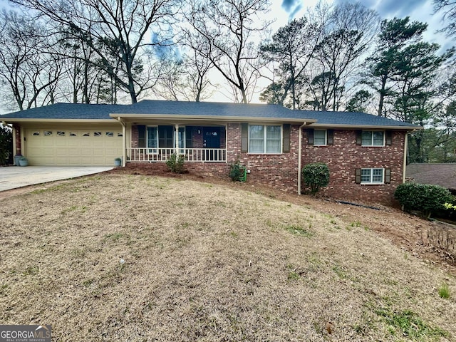 single story home featuring a porch, a garage, brick siding, concrete driveway, and a front lawn