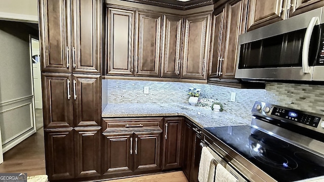 kitchen with light stone countertops, dark brown cabinets, stainless steel appliances, and decorative backsplash