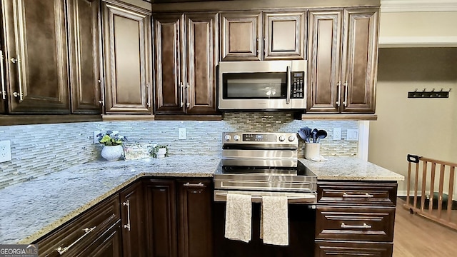 kitchen with stainless steel appliances, light stone counters, backsplash, and dark brown cabinetry