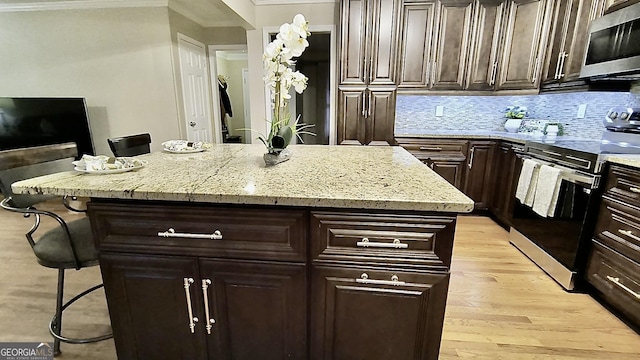 kitchen with appliances with stainless steel finishes, backsplash, a kitchen island, and light stone countertops