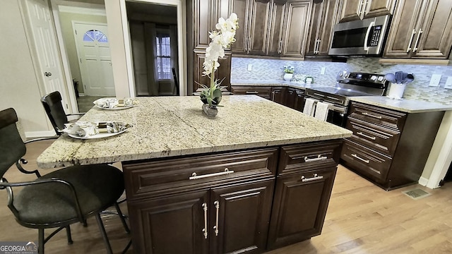 kitchen with a breakfast bar, a kitchen island, light stone counters, and stainless steel appliances