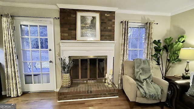 living area featuring ornamental molding, wood finished floors, and a glass covered fireplace