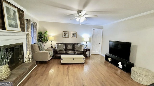 living area with ceiling fan, a brick fireplace, wood finished floors, and crown molding