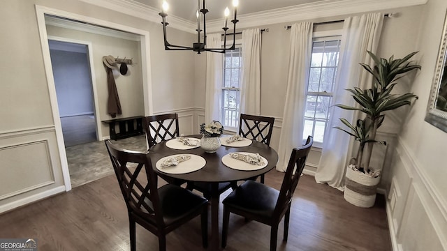 dining room featuring a decorative wall, wainscoting, dark wood-style floors, an inviting chandelier, and crown molding