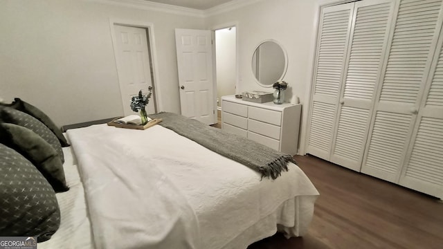 bedroom with a closet, dark wood finished floors, and crown molding