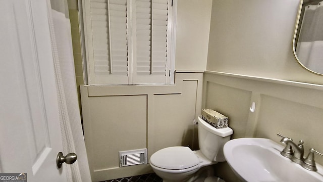 bathroom featuring toilet, a sink, visible vents, and a shower with curtain