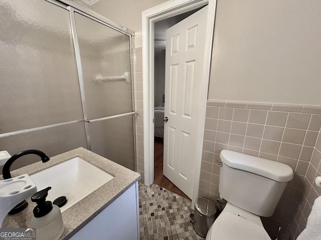 full bath featuring toilet, vanity, tile walls, wainscoting, and a shower stall